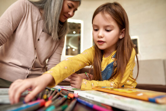 Lovely girl drawing at home with babysitter