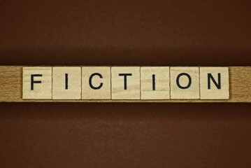 gray word fiction made of wooden letters on brown background