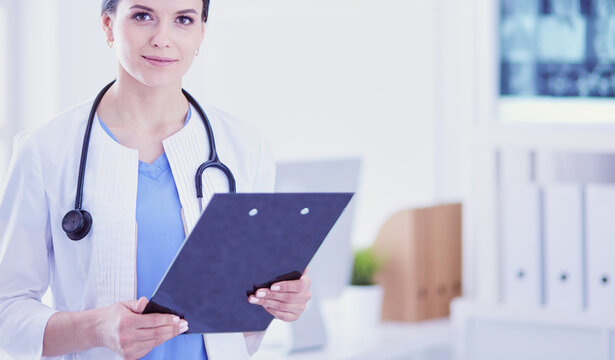 Young smiling female doctor with stethoscope holding a folder at doctor's office