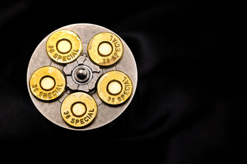 .38 special gun bullets with stainless revolver cylinder on black background , Top view - obrazy, fototapety, plakaty