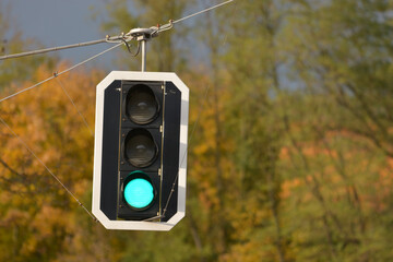 close-up of a traffic light with a hazy autumn background and green light