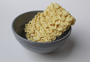 Square instant noodles before cooked, inside grey bowl, isolated on white background