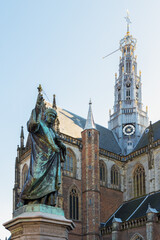 The Grote Kerk (St.Bavokerk), on the central market square, with statue in front in the city of Haarlem. - obrazy, fototapety, plakaty