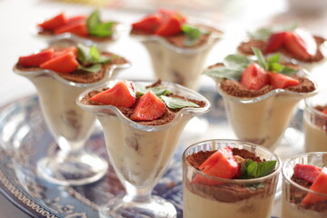 Strawberry tiramisu in a glass decorated with mint leaves and strawberry slices . Classic Italian dessert