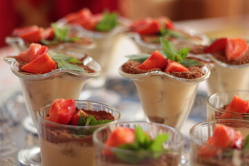 Strawberry tiramisu in a glass decorated with mint leaves and strawberry slices . Classic Italian dessert
