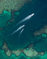 epic drone shot of three boats navigating up the coast