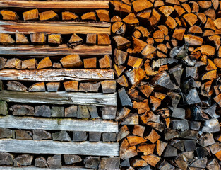Stacked gray and brown firewood of various shapes