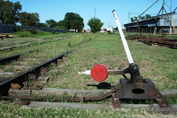 Dispositivo de palanca para cambiar las vías del antiguo ferrocarril con la parte inferior del tren en la estación con cielo azul.