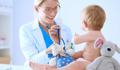 Female doctor is listening kid with a stethoscope in clinic - 471079656