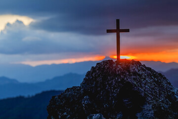 Silhouettes of crucifix symbol on top mountain with bright sunbeam on the colorful sky background