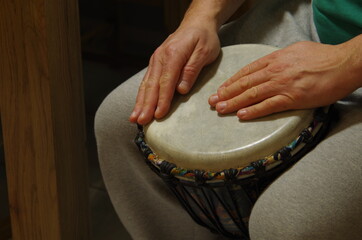 male hands playing on djembe drum