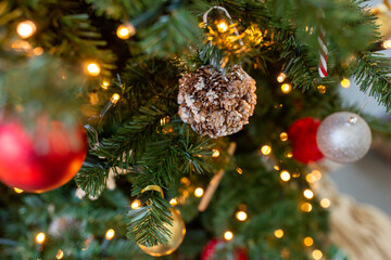winter holidays, new year and celebration concept - close up of decoration made of cones hanging on artificial christmas tree