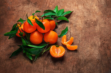 Mandarines oranges fruits or tangerines with green leaves on a dark wooden background. Copyspace.