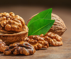 Walnuts on dark vintage table. Walnuts kernels with green leaves. Copyspace.  Nut healthy food concept. Closeup.