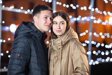 Fototapeta premium Couple looking away and smiling in the night city.