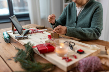 Fototapeta premium winter holidays and hobby concept - close up of woman with box and rope packing christmas gift or making advent calendar at home