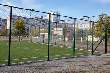 Lawn field for playing football behind the green fence mesh. Close-up of soccer field with green grass