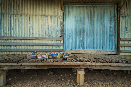 Piles of old newspapers tied up with string sitting on the weather boards at the front of a tin shed