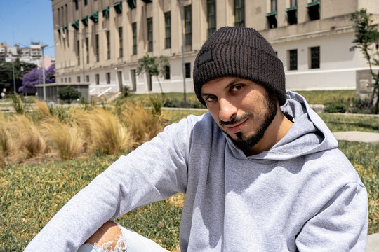 Young Latin Man With A Gray Jumpsuit And A Black Wool Cap Urban Style.