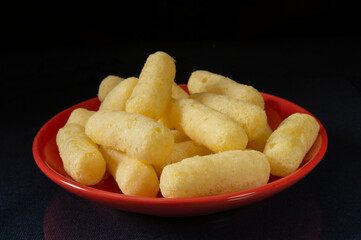 Sweet corn sticks in a red plate on the table.
