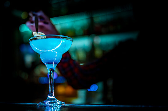woman bartender hand at the bar or pub to prepare a cocktail Blue Lagoon