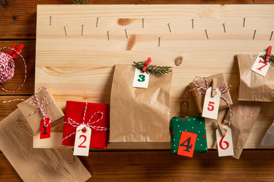 winter holidays, diy and hobby concept - close up of christmas gifts and decorative stuff for advent calendar making on wooden table at home