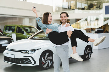 Happy young caucasian woman and man husband and wife couple family buying new car, while boyfriend...