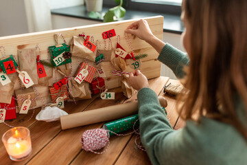 winter holidays, christmas and hobby concept - hands hanging gift with tag to handmade advent...
