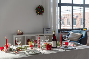 winter holidays, dinner party and celebration concept - christmas table serving with candles, crockery and wine at home
