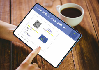 Hands of woman using tablet with covid vaccination certificate and qr code on screen