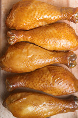Smoked chicken legs whole on wooden board. Rustic organic food, top view.