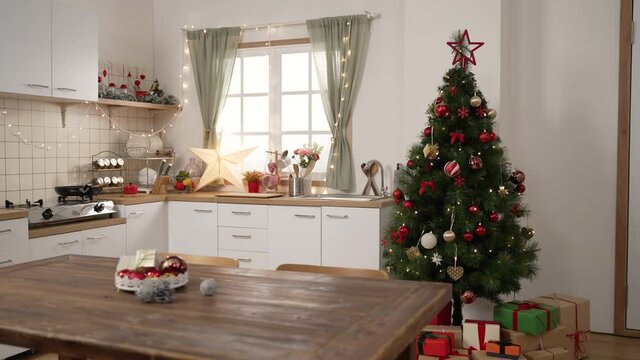 Christmas room interior. Comfortable cooking place decorated by xmas tree and colorful gifts on dining table by bright window. beautiful apartment prepare for new year holidays 