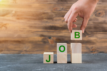JOB. Job search concept, a man's hand lowers a wooden cube with the letter B forming the word JOB