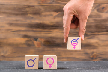 The concept of gender equality, the symbol of a man and a woman on wooden cubes. A man's hand puts a block with a symbol of gender equality.