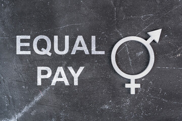 The symbol of gender equality in silver and the text EQUAL PAY on a dark background