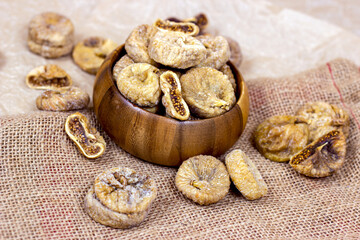 Sweet dried italian figs in the wooden bowl on the brown cutting board background.