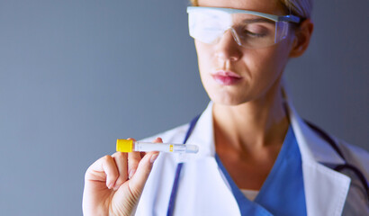 Female medical or research scientist or doctor using looking at a test tube of clear solution in a lab or laboratory.