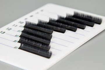 A tablet with false eyelashes on a gray background. Cosmetic accessories for eyelash extensions