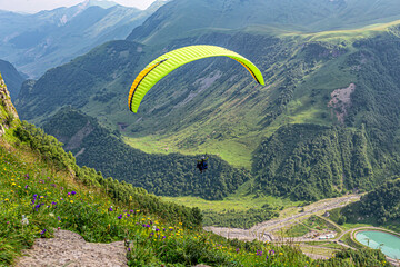 Bright green paraglider over a gorge in the Caucasus Mountains