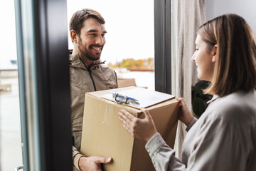 shipping, transportation and people concept - delivery man with parcel box and clipboard talking to...