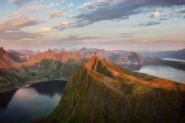 Amazing sunset over calm waters of Norwegian nortern fjords, Ersfjorden and Bergsfjorden, and small town tucked away among hills. Viewpoint from Husfjellet, Senja island. Tourism, travel concept. 