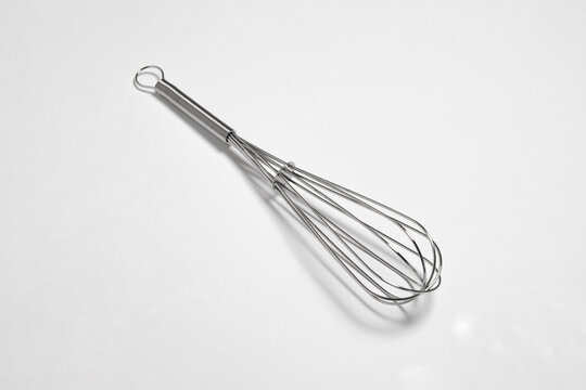 Clean new steel whisk isolated on white background. Cooking egg beater mixer whisker with plastic handle.High-resolution photo. Mockup