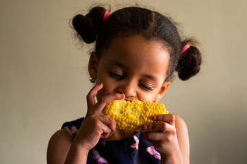 lovely little girl eating corn on the cob
