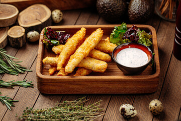 Deep fried mozzarella cheese sticks with sauce on wooden background
