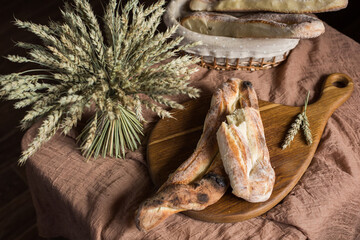 Homemade bread on a wooden board next to wheat. Bakery. Fresh, aromatic, hot bread.