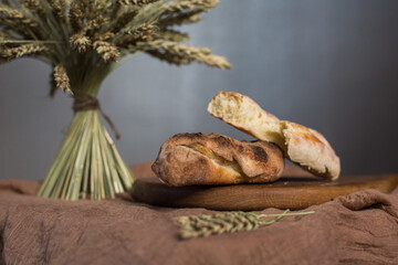 Homemade bread on a wooden board next to wheat. Bakery. Fresh, aromatic, hot bread.