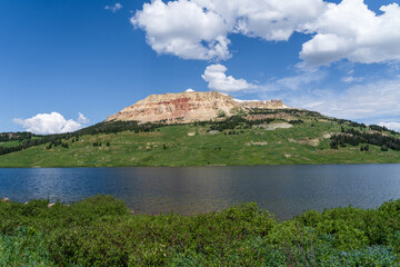 Beartooth Lake on a sunny summer day in the Beartooth Highway in the mountains of Wyoming and Montana - an alpine lake with a green and red rock mountain in the background