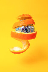 orange peel around a disco mirror ball, floating on yellow background