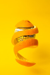 orange peel around a disco mirror ball, floating on yellow background