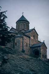 Fototapeta na wymiar Ancient stone monastery in Georgia. Ancient church of dark stone on the hill. Old architecture, historical heritage
